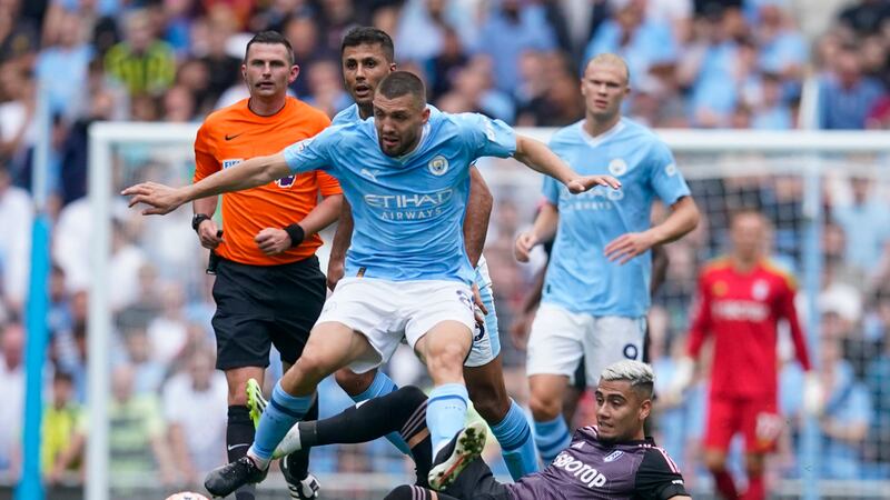 Manchester City's Mateo Kovacic, center, duels for the ball with Fulham's Andreas Pereira,...